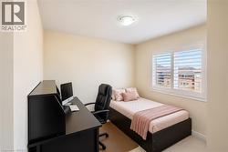 Room featuring a window with white plantation shutters, neutral-toned walls, and a flush-mount ceiling light fixture - 