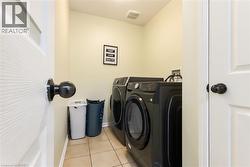 Dedicated laundry area featuring tile flooring and light-toned wall paint - 