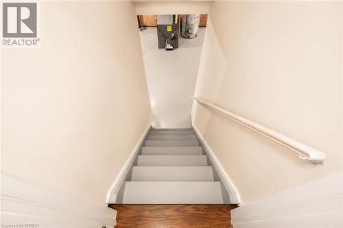 Stairwell with painted treads and risers, white handrail, light-toned wall paint, and wood-finish flooring at the base - 26 Pollard Street, Brantford, ON - Indoor Photo Showing Other Room
