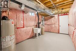 Utility room featuring a water heater, laundry tub, visible ductwork, and exposed ceiling joists - 