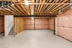Unfinished basement space featuring exposed wood joists, insulated walls, and a concrete floor - 