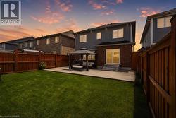 Spacious backyard featuring a manicured lawn, a large concrete patio, and a privacy fence - 