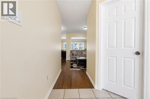 Hallway featuring light beige wall paint, wood-finish flooring, and a white paneled door with a dark knob - 26 Pollard Street, Brantford, ON - Indoor Photo Showing Other Room