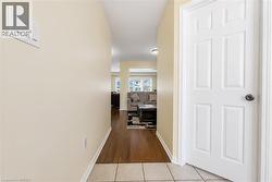 Hallway featuring light beige wall paint, wood-finish flooring, and a white paneled door with a dark knob - 