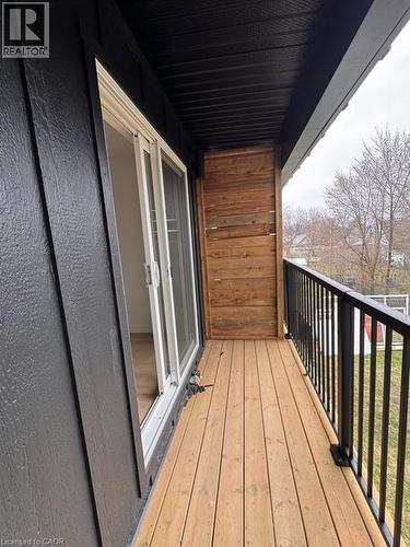 Exterior balcony featuring natural wood decking, black metal railings, and a sliding glass door - 431 Krug Street, Kitchener, ON - Outdoor With Exterior