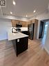 Modern kitchen featuring stainless steel appliances, light wood-finish cabinetry, recessed ceiling lighting, a dark kitchen island with a white countertop, and wood-finish flooring - 431 Krug Street, Kitchener, ON  - Indoor Photo Showing Kitchen 
