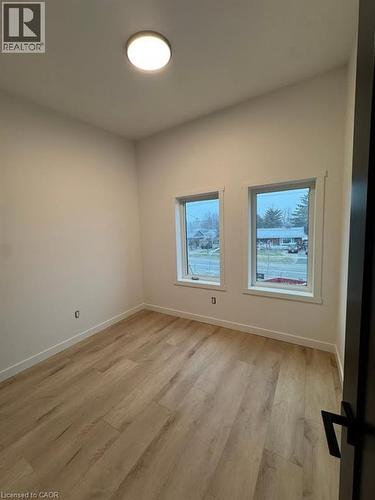 Room featuring wood-finish flooring, white walls, two windows, a ceiling-mounted light fixture, and white baseboards - 431 Krug Street, Kitchener, ON - Indoor Photo Showing Other Room