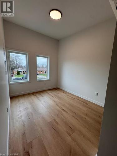 Bright room featuring two windows, wood-finish flooring, white baseboards, and a flush-mount ceiling light - 431 Krug Street, Kitchener, ON - Indoor Photo Showing Other Room