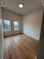 Bright room featuring two windows, wood-finish flooring, white baseboards, and a flush-mount ceiling light - 