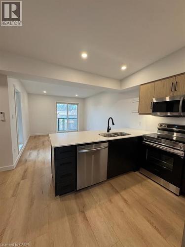 Modern kitchen island featuring a double-basin sink, stainless steel dishwasher, and quartz countertop - 431 Krug Street, Kitchener, ON - Indoor Photo Showing Kitchen With Double Sink