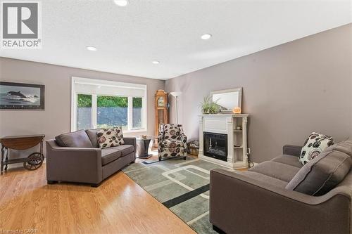 Living area featuring wood-finish flooring, recessed lighting, a large window, and a white decorative fireplace surround with an electric insert - 26 Sideroad 18, Fergus, ON - Indoor Photo Showing Living Room With Fireplace