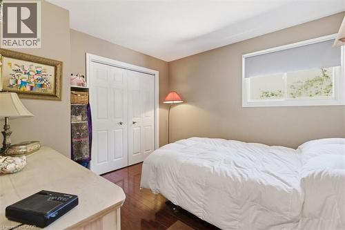 Interior room featuring wood-finish flooring, a double-door closet with white paneled doors, and an exterior window with a roller shade - 26 Sideroad 18, Fergus, ON - Indoor Photo Showing Bedroom