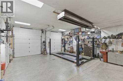 Spacious garage featuring two overhead doors, a four-post vehicle lift, concrete flooring, and built-in shelving - 26 Sideroad 18, Fergus, ON - Indoor Photo Showing Garage