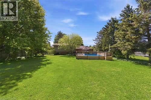 Expansive green lawn with a large, above-ground swimming pool featuring a surrounding wooden deck - 26 Sideroad 18, Fergus, ON - Outdoor With Backyard