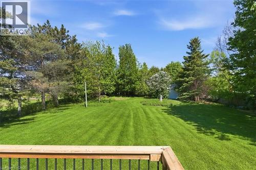 Expansive green lawn surrounded by mature trees, featuring a wooden deck railing - 26 Sideroad 18, Fergus, ON - Outdoor