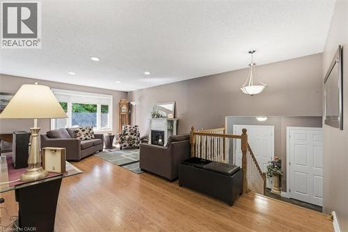 Hardwood-finish flooring extending into a spacious living area featuring a fireplace with a white mantel, recessed lighting, and a chandelier - 26 Sideroad 18, Fergus, ON - Indoor