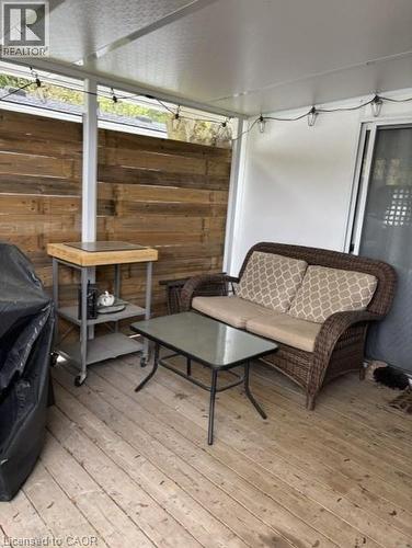 Covered outdoor deck featuring natural wood plank flooring, a horizontal wood plank accent wall, and a durable metal roof - 580 Beaver Creek Road Unit# 203, Waterloo, ON - Outdoor With Deck Patio Veranda With Exterior