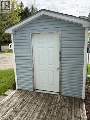 Exterior storage shed featuring blue siding, a white paneled door, and a weathered wooden deck - 580 Beaver Creek Road Unit# 203, Waterloo, ON - Outdoor With Exterior