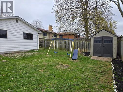 Expansive backyard featuring a manicured lawn, a privacy fence, and a dedicated storage shed on a concrete pad - 261 Overlea Drive, Kitchener, ON 