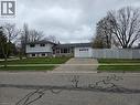 Split-level residence featuring a brick and siding exterior, an attached single-car garage, a concrete driveway, a manicured lawn, and a white picket fence - 261 Overlea Drive, Kitchener, ON 