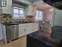 Kitchen featuring white cabinetry, dark countertops, a mosaic tile backsplash, a stainless steel dishwasher, and wood-finish flooring - 261 Overlea Drive, Kitchener, ON 