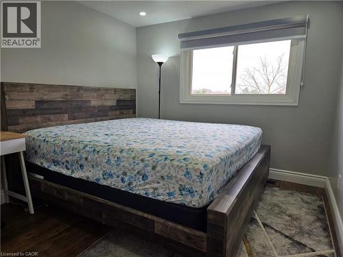 Room featuring light gray painted walls, a white-framed window with a roller shade, and dark wood-finish flooring - 261 Overlea Drive, Kitchener, ON 