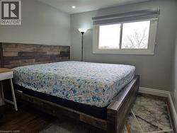 Room featuring light gray painted walls, a white-framed window with a roller shade, and dark wood-finish flooring - 
