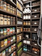 Custom pantry featuring extensive dark wood-finish shelving, integrated storage for small appliances, and woven basket storage solutions - 