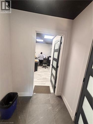 Hallway featuring large format tile flooring, white baseboards, and a contrasting dark ceiling - 277 Lancaster Street W, Kitchener, ON 