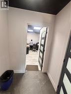 Hallway featuring large format tile flooring, white baseboards, and a contrasting dark ceiling - 