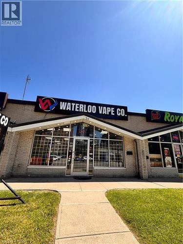Commercial storefront featuring a prominent illuminated sign, extensive front window displays, and a central glass entry door - 29 University Avenue E, Waterloo, ON 