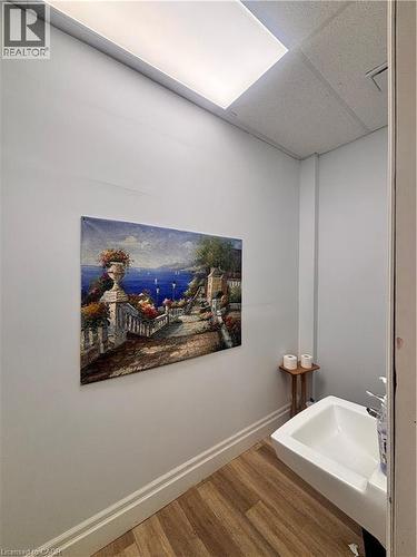 Wall-mounted sink with a chrome faucet, set against light gray walls with white baseboards, and wood-finish flooring - 1400 Weber Street E Unit# A5, Kitchener, ON 