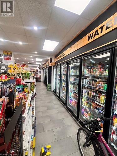 Retail interior featuring a long aisle with commercial refrigerators, track lighting, ceiling panels, and tile flooring - 277 Lancaster Street W, Kitchener, ON 