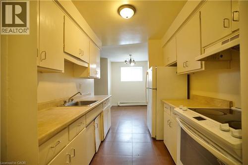 Galley kitchen featuring white cabinetry, laminate countertops, a double-basin stainless steel sink, and a built-in range with overhead ventilation - 223 Heiman Street Unit# Unit 2, Kitchener, ON - Indoor Photo Showing Kitchen