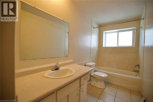 Bathroom featuring a large vanity with an integrated sink, an expansive wall-mounted mirror, a tiled tub-shower combination, a white toilet, and a window with privacy glass - 223 Heiman Street Unit# Unit 2, Kitchener, ON - Indoor Photo Showing Bathroom