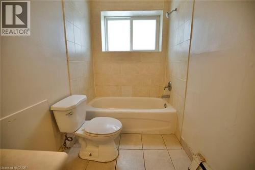 Bathroom featuring a white bathtub, ceramic wall tiling, shower fixture, and a white toilet - 223 Heiman Street, Kitchener, ON - Indoor Photo Showing Bathroom