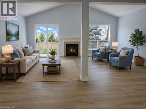 Spacious living area featuring vaulted ceilings, a central fireplace with white mantel, wood-finish flooring, and sliding glass doors to the exterior - 732 Angler Way, Waterloo, ON - Indoor Photo Showing Living Room With Fireplace