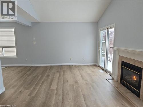Open-concept living space featuring wood-finish flooring, a vaulted ceiling, and light gray walls - 732 Angler Way, Waterloo, ON - Indoor With Fireplace