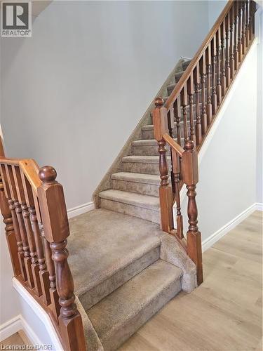 Staircase featuring wood railings and balusters, carpeted treads, and light grey wall paint - 732 Angler Way, Waterloo, ON - Indoor Photo Showing Other Room