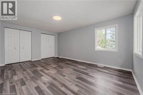 Spacious interior room featuring wood-finish flooring, two large bi-fold door closets, recessed ceiling lighting, and multiple windows with white trim - 732 Angler Way, Waterloo, ON - Indoor Photo Showing Other Room