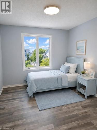 Room featuring wood-finish flooring, a double window with exterior scenery, light blue walls, white trim, and a flush-mount ceiling light - 732 Angler Way, Waterloo, ON - Indoor Photo Showing Bedroom