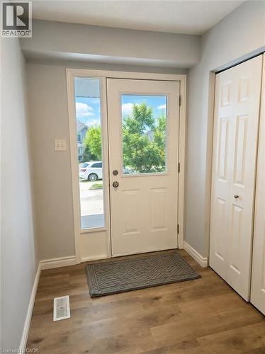 Entryway featuring a white door with a clear glass insert, a full-length sidelight, wood-finish flooring, and bi-fold closet doors - 732 Angler Way, Waterloo, ON - Indoor Photo Showing Other Room
