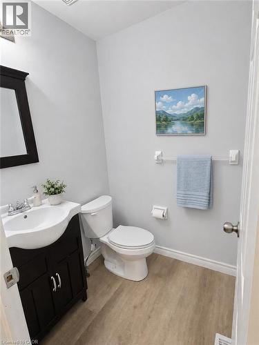 Powder room featuring a dark wood-finish vanity with an integrated white sink, chrome fixtures, and wood-finish flooring - 732 Angler Way, Waterloo, ON - Indoor Photo Showing Bathroom