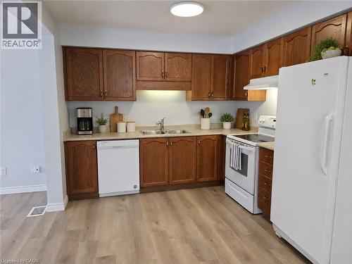 Kitchen featuring wood-finish cabinetry, light-toned countertops, a white refrigerator, a white range, and a white dishwasher - 732 Angler Way, Waterloo, ON - Indoor Photo Showing Kitchen With Double Sink