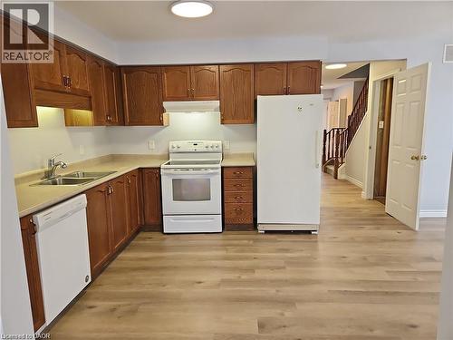 Kitchen featuring wood cabinetry, laminate countertops, a double basin stainless steel sink, and wood-finish flooring - 732 Angler Way, Waterloo, ON - Indoor Photo Showing Kitchen With Double Sink