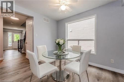 Bright dining area featuring wood-finish flooring, a large window with white trim, and a ceiling fan with integrated lighting - 732 Angler Way, Waterloo, ON - Indoor Photo Showing Dining Room