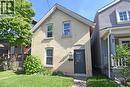 Brick exterior with decorative gable trim, a dark-colored entry door, and a manicured lawn - 12 Wood Street W, Hamilton, ON 