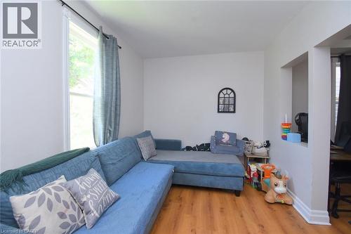 Living area featuring wood-finish flooring, white baseboards, and a large window with natural light - 12 Wood Street W, Hamilton, ON - Indoor Photo Showing Living Room