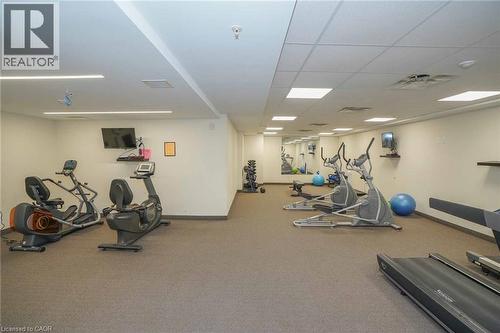 Dedicated fitness area featuring durable carpet flooring, recessed lighting, wall-mounted televisions, and mirrored accents - 7 Kay Crescent Unit# 107, Guelph, ON 