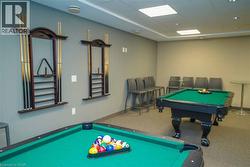 Recreation room featuring two billiards tables with green felt surfaces, recessed ceiling lighting, and overhead square light panels - 